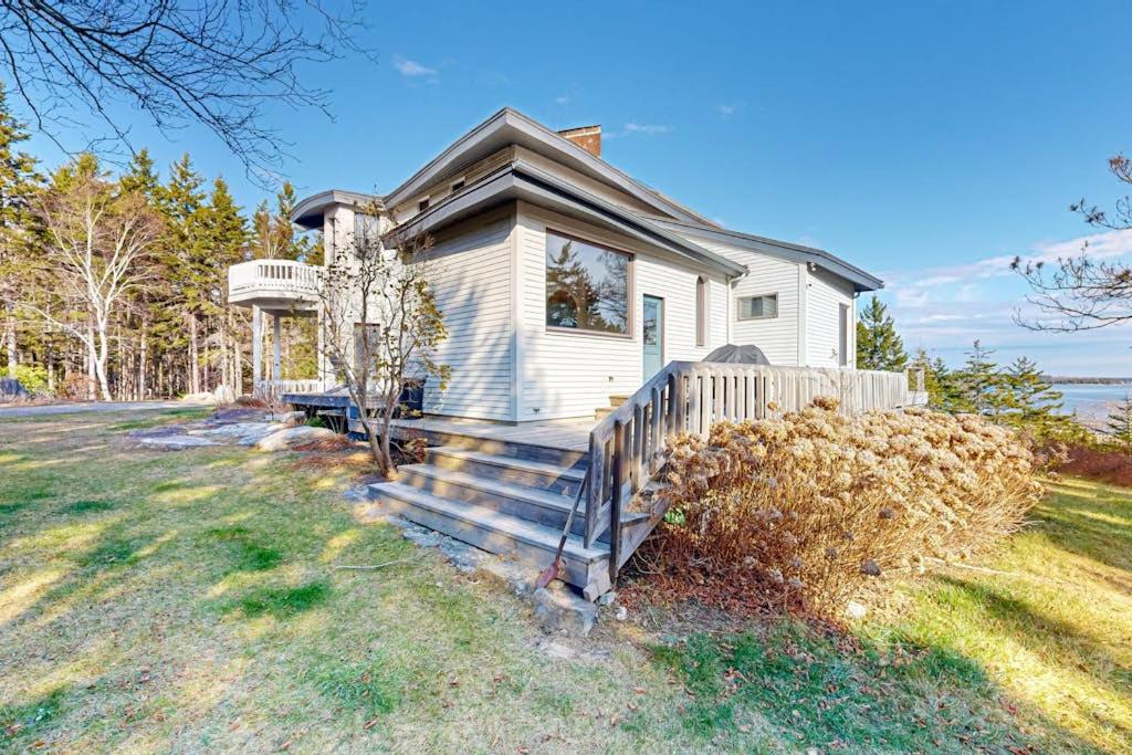 a small white house with a porch and stairs at Private Oceanfront Home -- 2 Fireplaces, 4 Decks & Grill, Dog-friendly in East Boothbay