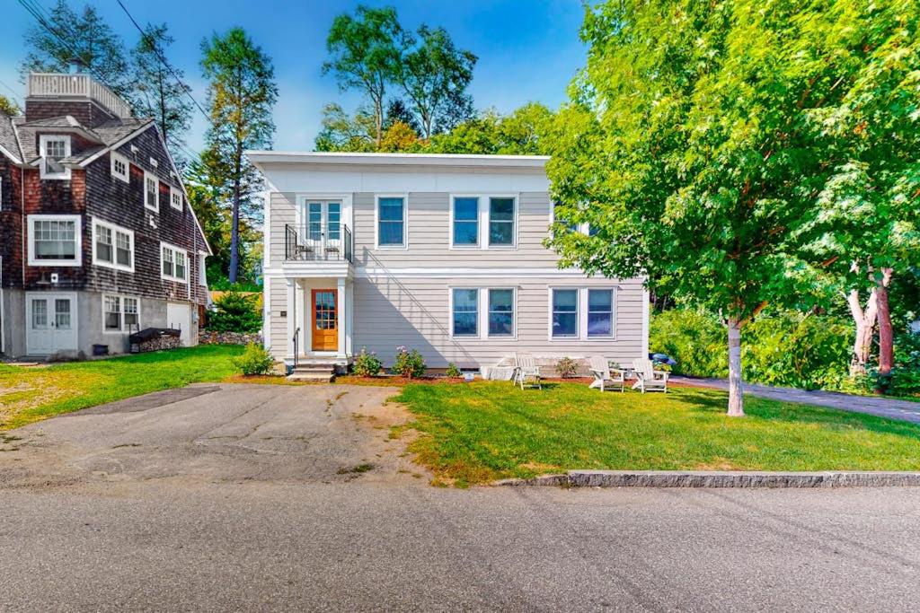 a white house with a tree and a house at Waterfront Duplex, walkable, harbor views, AC, dog friendly in Camden