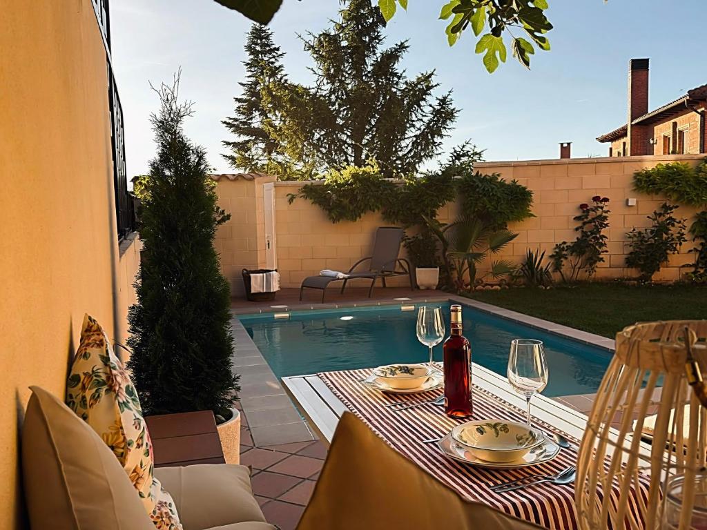 a table with wine glasses next to a swimming pool at La Casita de Numancia in Garray
