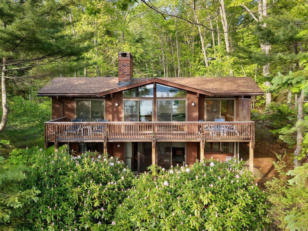a house with a large deck in the woods at Beautiful hidden Waterfront Retreat with Rocky Beach in Boothbay