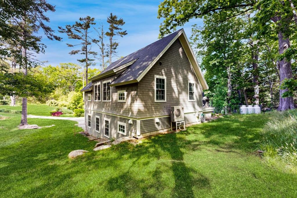 a small house in a field of green grass at Brand new guest apartment with furnished deck, fast WIFI, dock, & water views in Boothbay Harbor