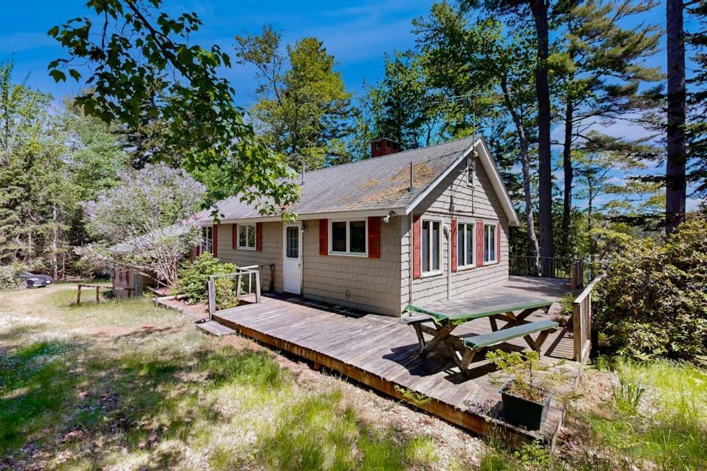 a tiny house with a picnic table on a deck at Lady Slipper Cottage: Charming Lakefront Retreat with Canoes, Kayaks, and Modern Comforts in Somesville