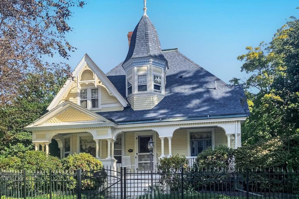 a yellow house with a turret on top of a fence at Dog-friendly historical home with recent updates, porch & prime in-town location in Rockland