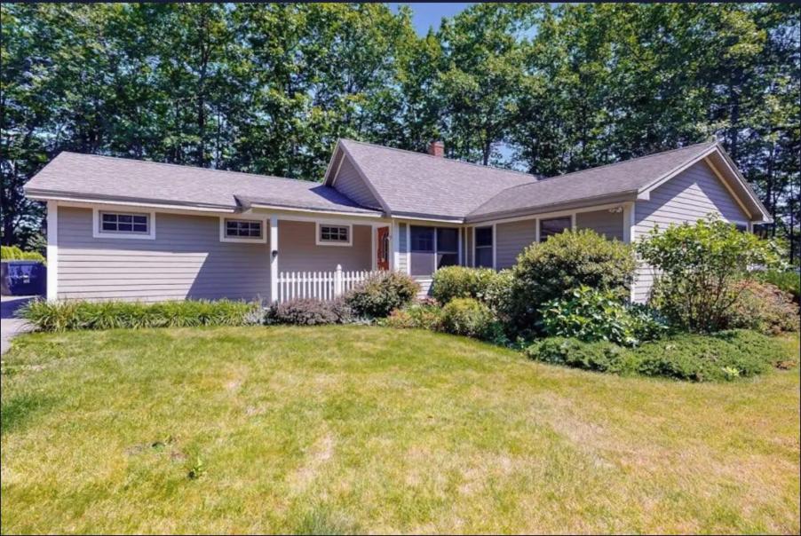 a house with a lawn in front of it at Secluded lakefront home with patio & firepit, fast WiFi, wood stove & W/D in Ellsworth