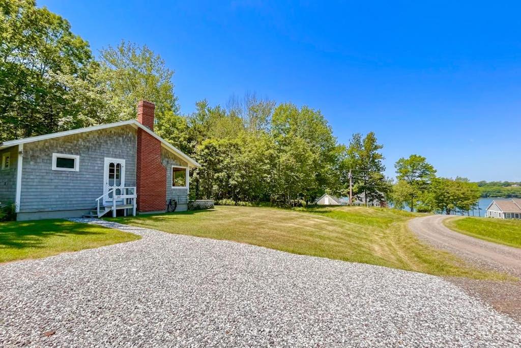 a small house with a gravel driveway next to a road at Classic home overlooking the St George River with deck & great views in Saint George