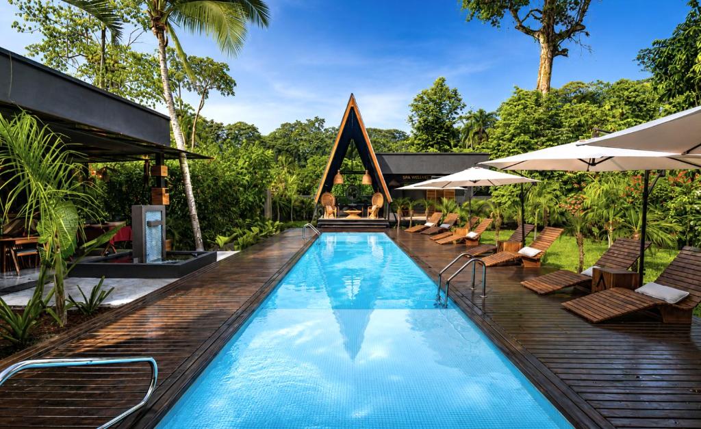 a pool at a resort with chairs and umbrellas at Namu Garden Hotel & Spa - Adults Only in Puerto Viejo