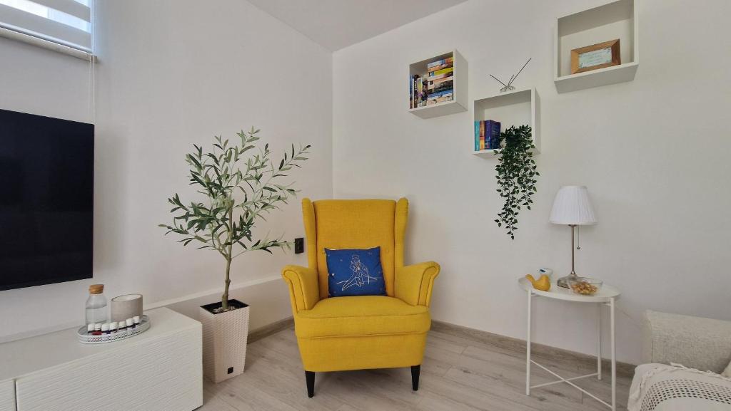 a living room with a yellow chair and a tv at Apartman Jurjević in Krk