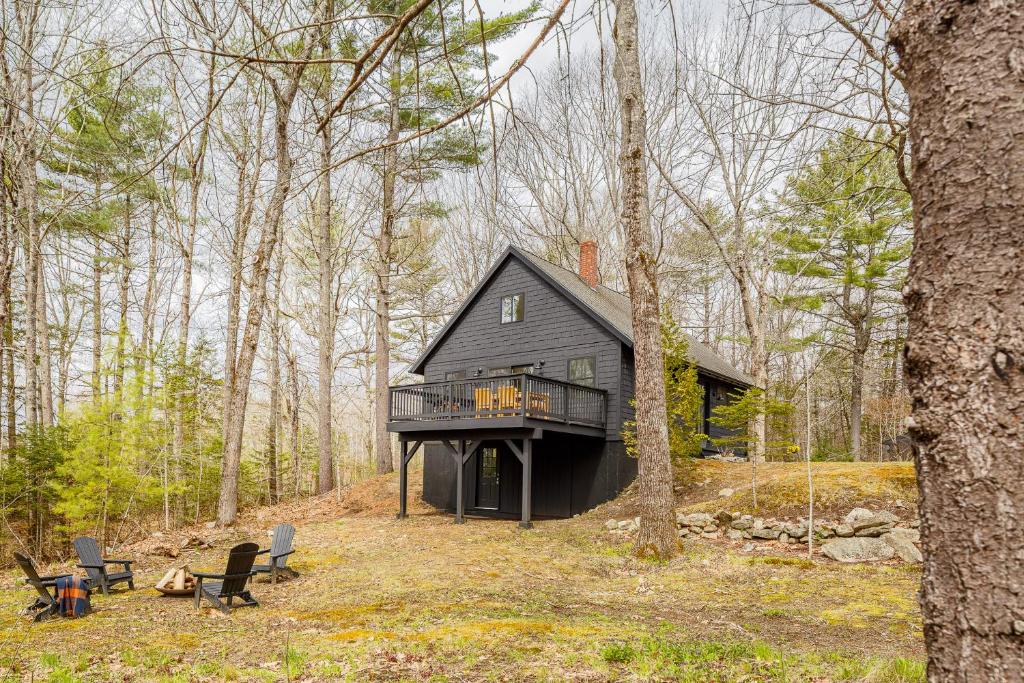 a black house in the middle of the woods at Renovated woodland home with lovely deck & firepit - minutes to Swan Lake in Swanville