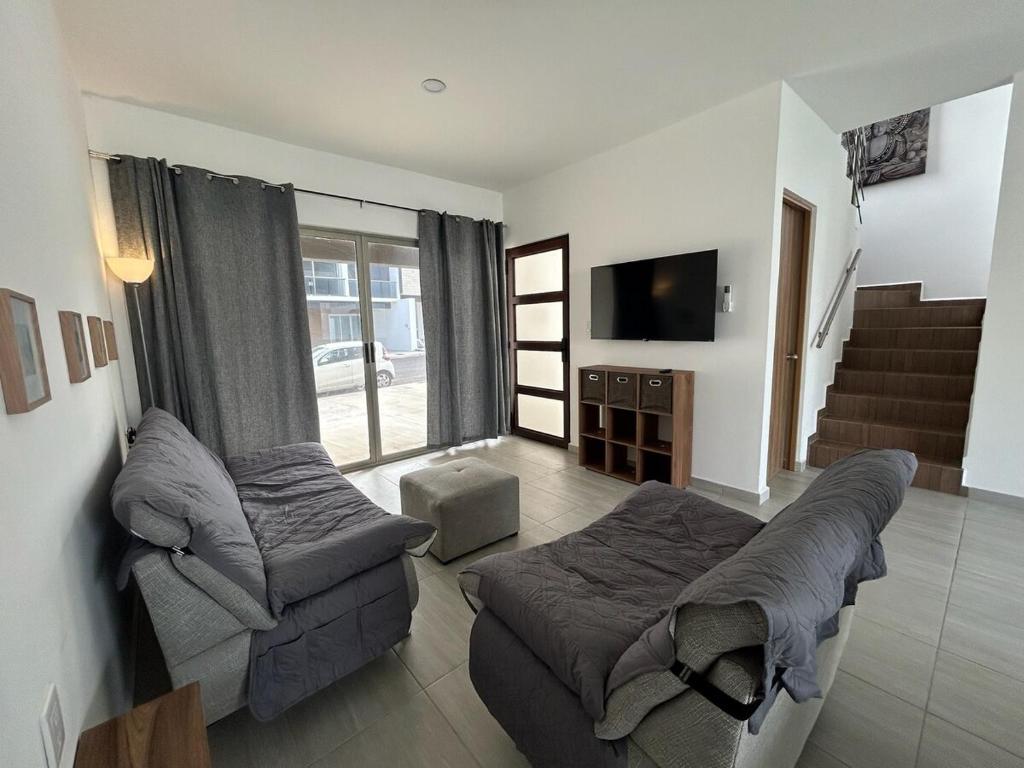 a living room with a couch and a tv at Private pool house near the beach in Heroica Alvarado