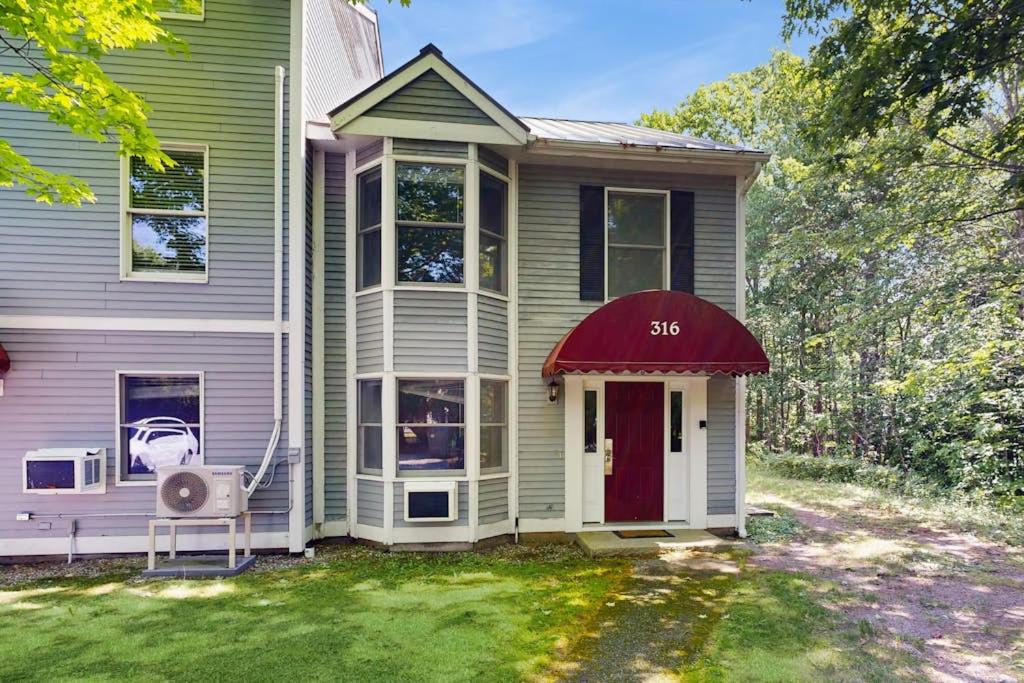 a house with a red door on a yard at Bay View Dog-Friendly Townhouse w/Porch, Gas Grill, Washer/Dryer, Partial A/C in Bar Harbor