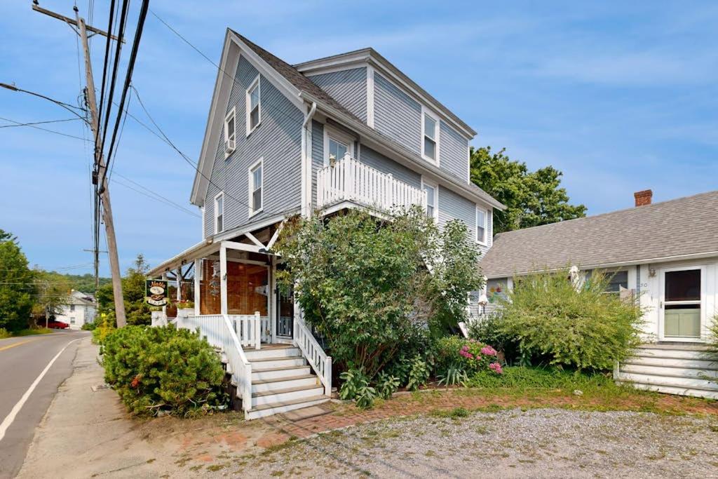 a gray house with a porch and stairs on a street at Charming, historic cottage with modern upgrades - stroll to dining & attractions in Boothbay Harbor