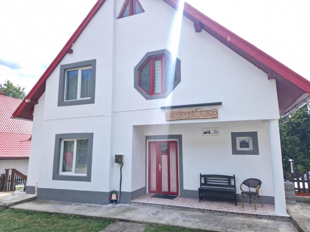 a small white house with a red door at Casa Flavius in Văliug