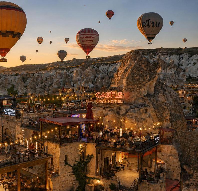 a group of hot air balloons flying over a city at Castle Cave Hotel in Göreme