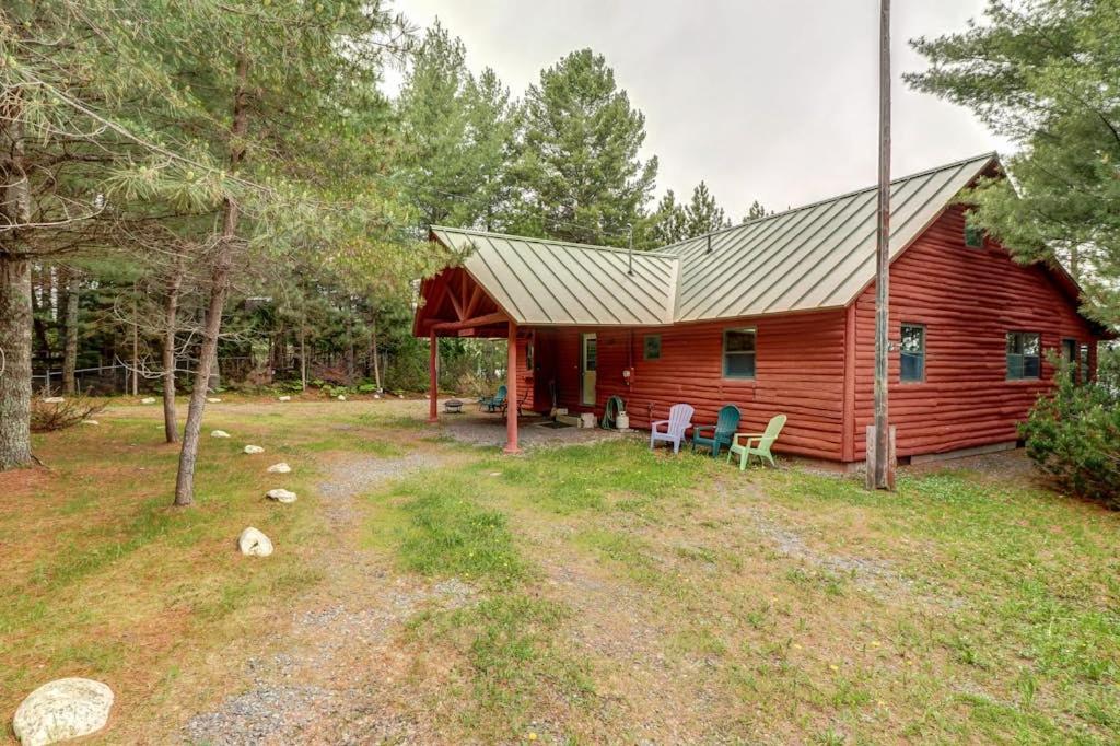 a red cabin with a porch and chairs in front of it at Lakefront Home with Private Dock, Pebble Beach & Enclosed Porch - Dogs Welcome in Greenville Junction