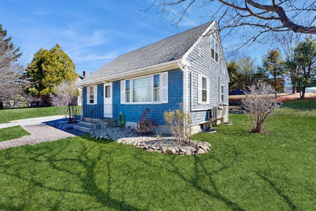 a blue house with a grass yard at Charming Coastal House with Cozy Living Spaces and Outdoor Firepit in Winter Harbor