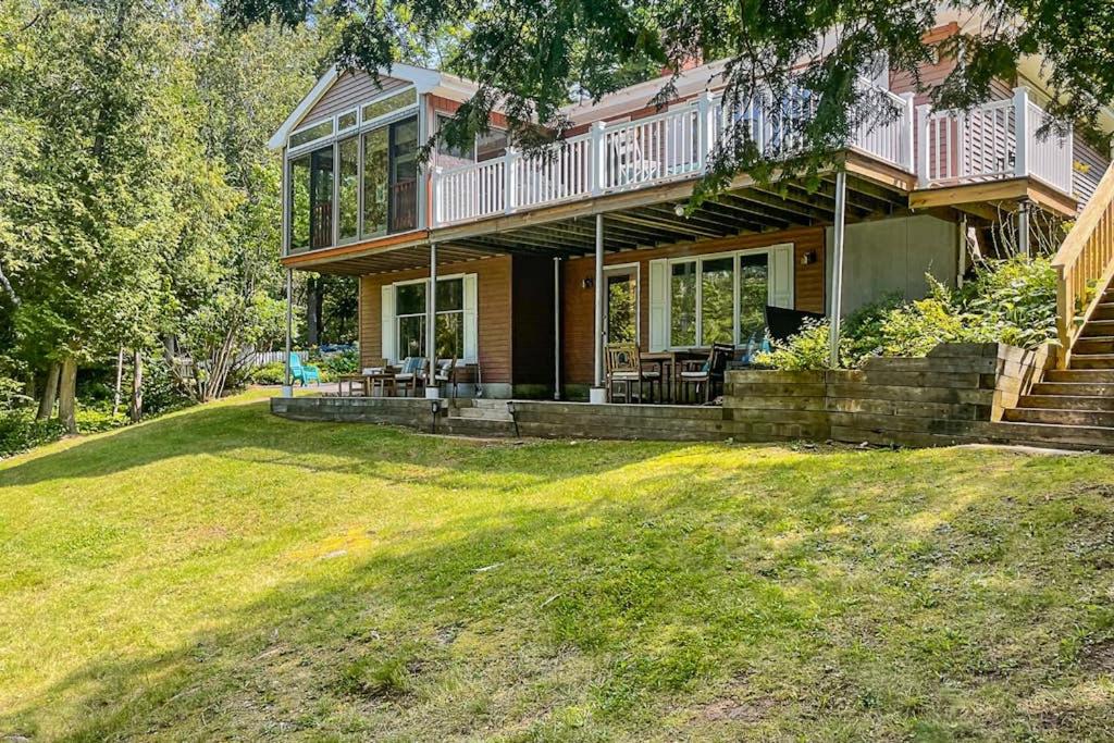 a large house with a balcony and a yard at Secluded waterfront home with private dock, outdoor dining, firepit, WiFi & W/D in Orland