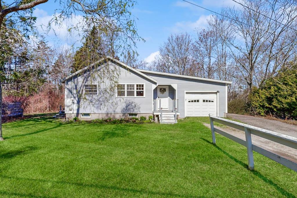 a white house with a grass yard at Coastal bungalow with large yard, beautiful kitchen, & great location in Boothbay Harbor