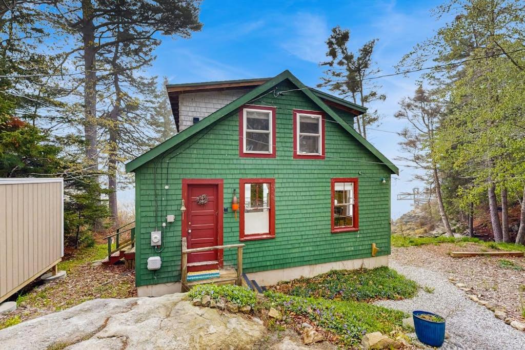 a green tiny house with a red door at Bayfront cottage with fantastic views & minutes to downtown - Dog-friendly in Boothbay Harbor