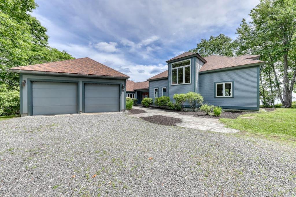 a house with a garage on a gravel driveway at Delightful oceanfront home with amazing views, wrap-around deck & two fireplaces in Wiscasset