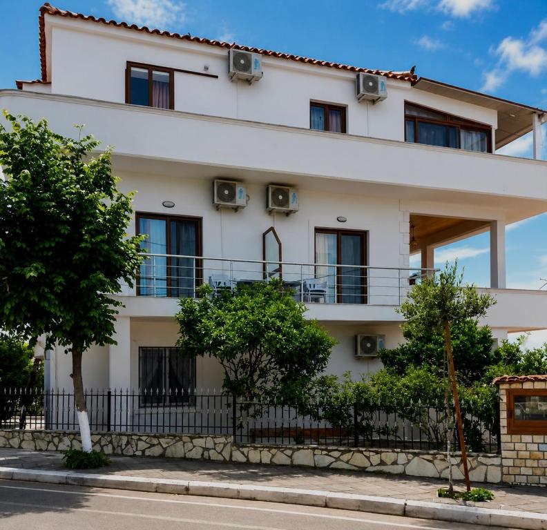 a white building with a fence and trees at Vila Vladmir Sela in Ksamil