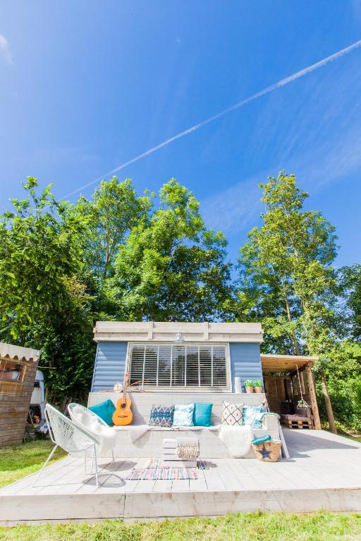 a blue house with a couch and chairs on a patio at Ibiza Summer Lodge in Brouwershaven