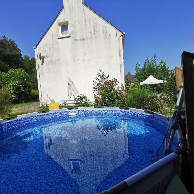 ein großer blauer Swimmingpool vor einem Gebäude in der Unterkunft Grand lodge du Pin 15 pers & salle fêtes in Languidic