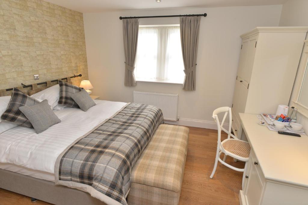 a bedroom with a bed with a desk and a window at The Woolly Sheep Inn in Skipton