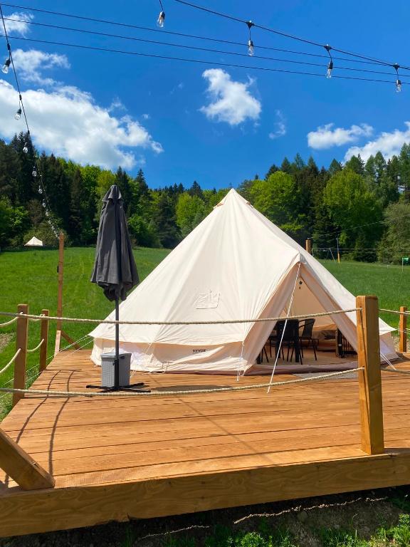 a white tent on a wooden deck with an umbrella at Glamping-Dimbo in Krynica Zdrój