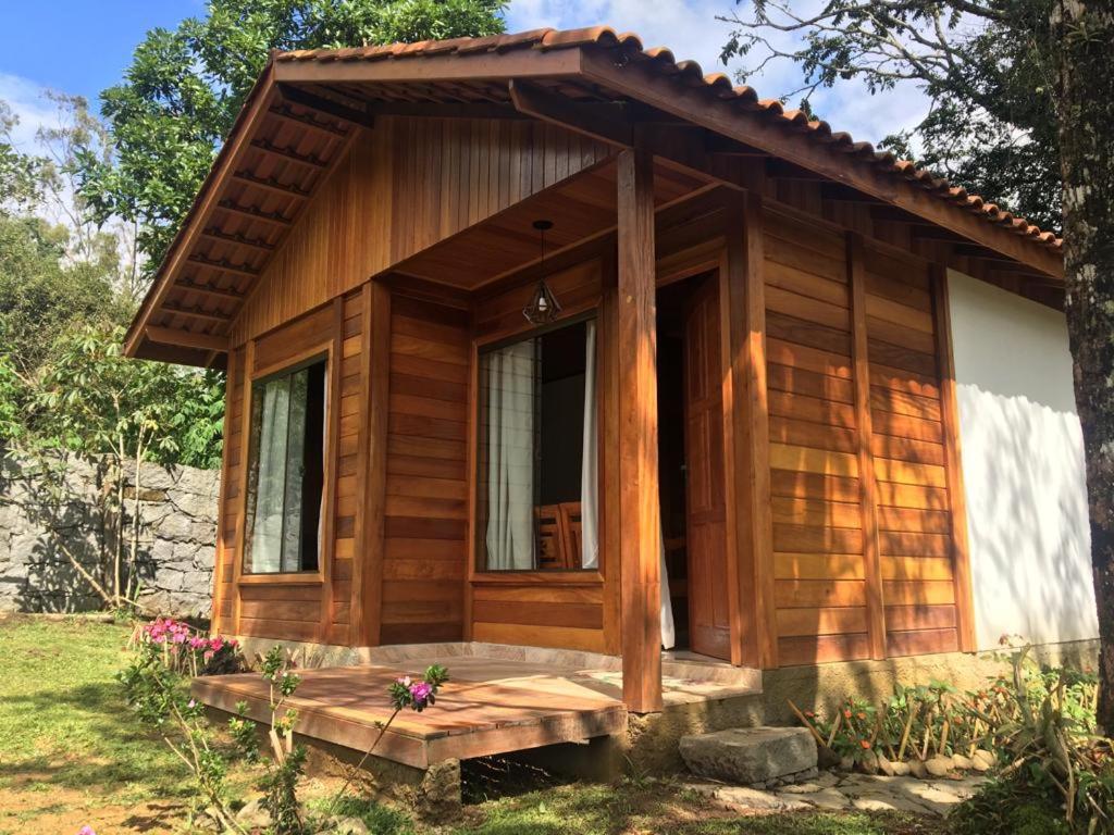 a small wooden cabin with a porch and a window at Pedacinho de Chão Chalés in Visconde De Maua