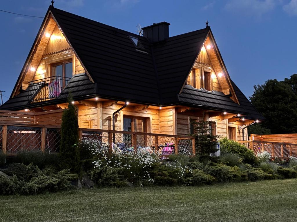 a wooden house with lights on it at night at Witowianskie Domki Private Jacuzzi & Mountain View near Zakopane in Dzianisz
