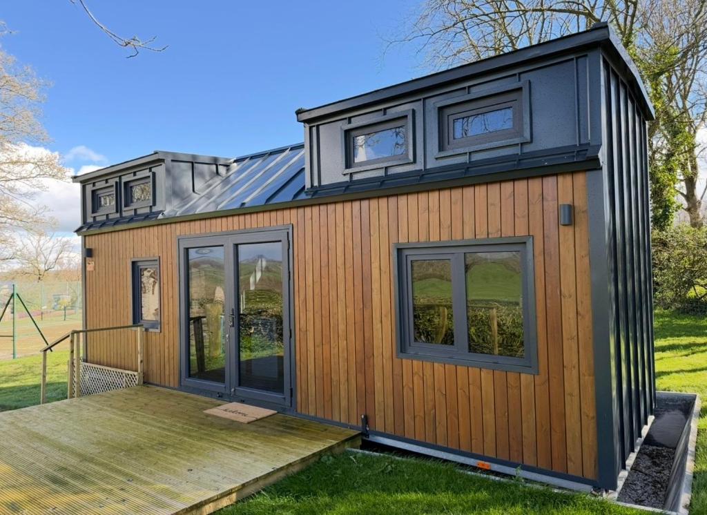 a tiny house with a black roof and windows at Kniveton Wood Hut in Ashbourne