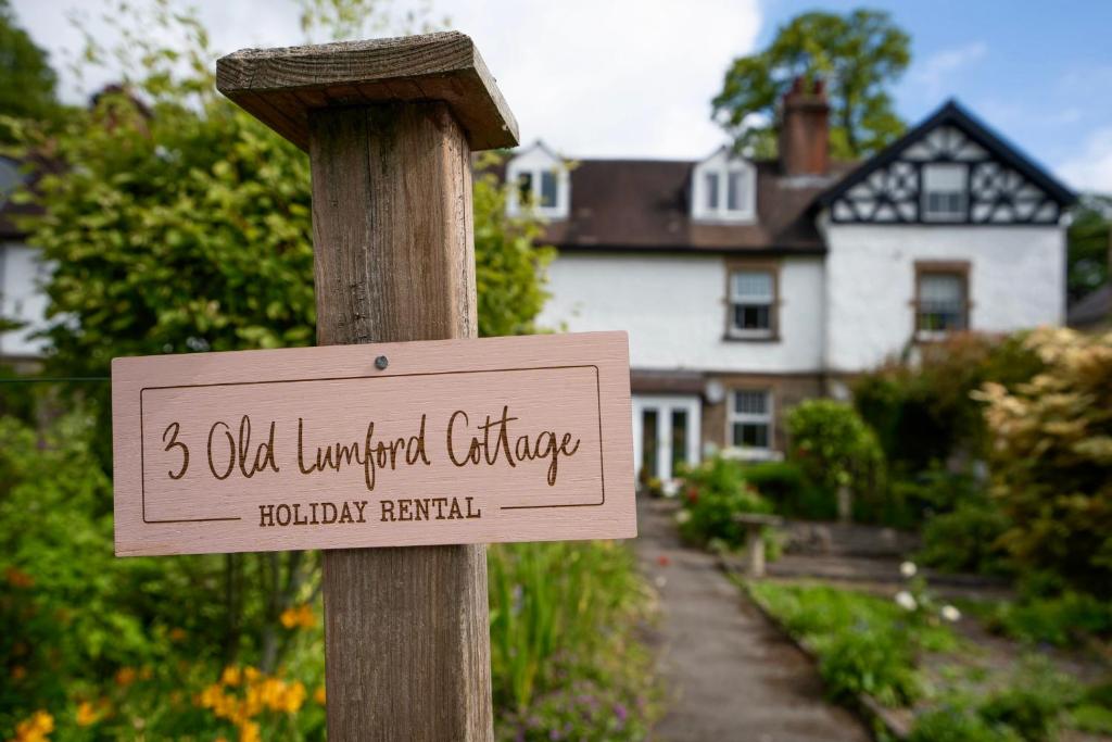 a sign on a wooden pole in front of a house at Old Lumford Cottage, Bakewell - Picturesque Riverside Property in Bakewell