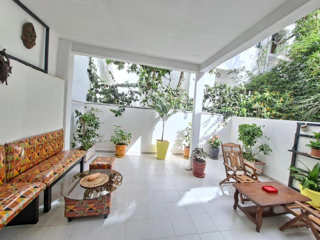 ein Balkon mit Bänken, Tischen und Topfpflanzen in der Unterkunft Téranga Home Cosy & Spacieux à 600m de la plage in Dakar