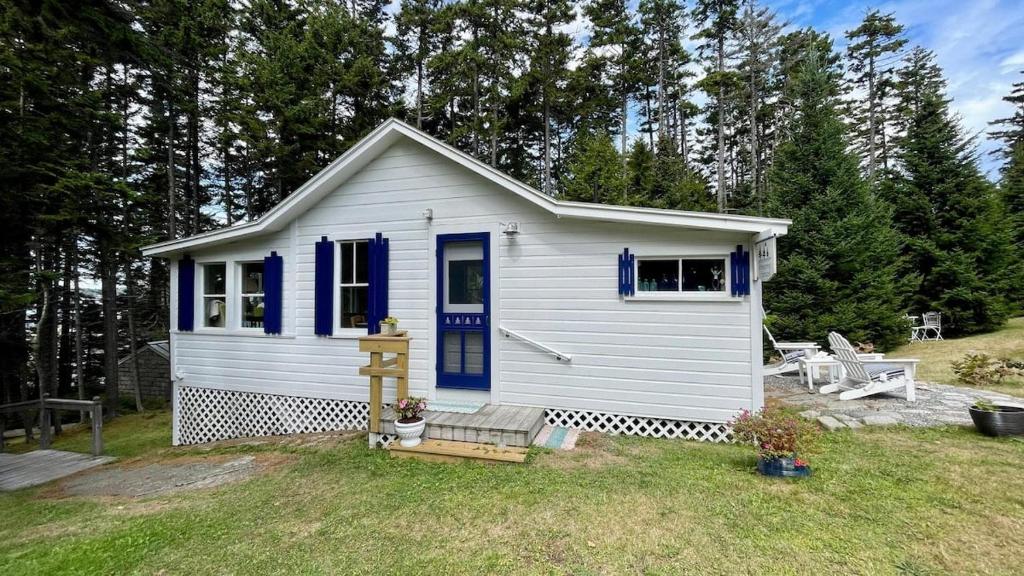 a small white house with a blue door at Whispering Spruces; Cozy Studio with Queen Bed & W in South Thomaston