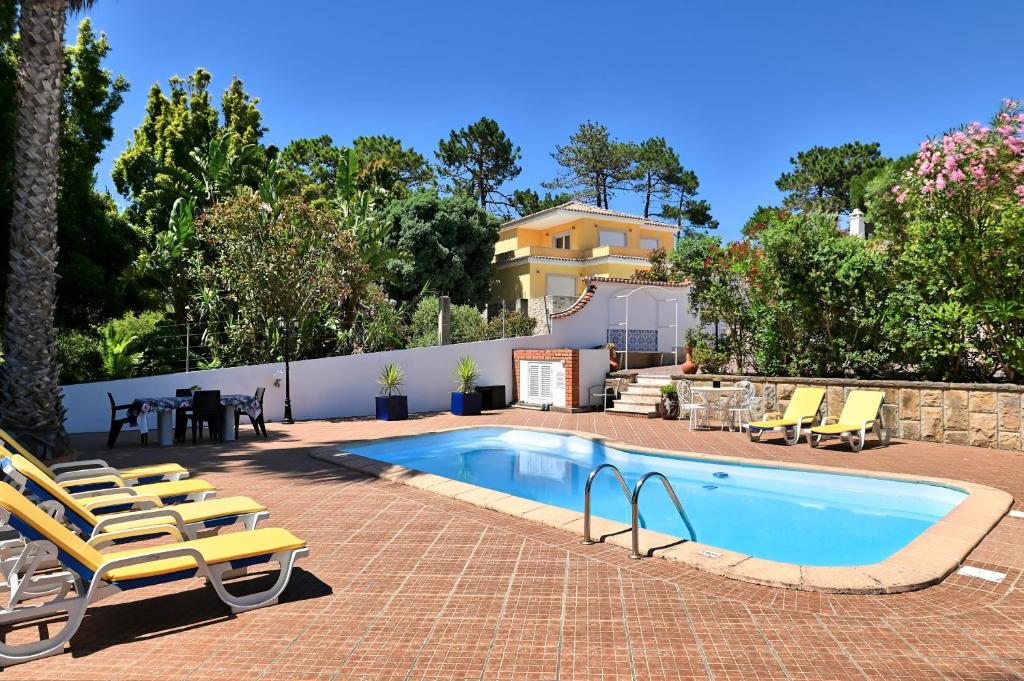 a swimming pool with lounge chairs and a house at Cottage Sete Mares in Colares