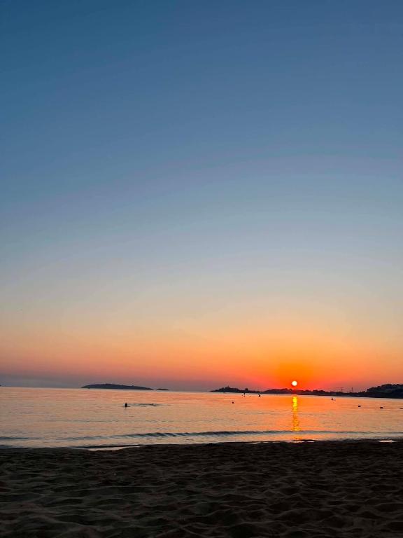 a sunset on a beach with the sun setting at Каравана Кукер in Sozopol
