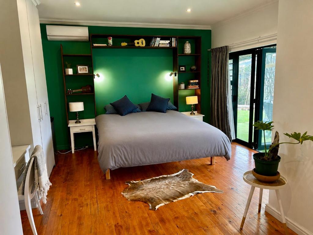 a green bedroom with a bed and a green wall at Bamboo in George