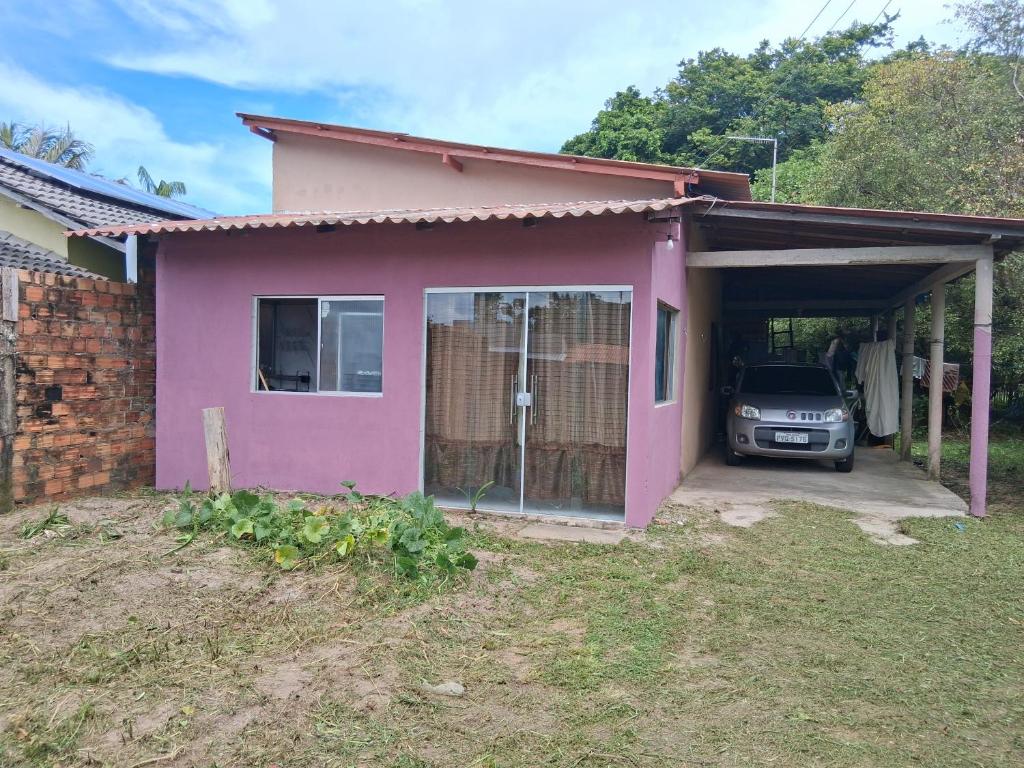 a pink house with a car parked in the garage at Casa próximo a praia in Salvaterra