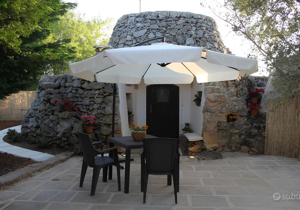 a table with chairs and an umbrella in front of a building at Trullo Salento in Galatone
