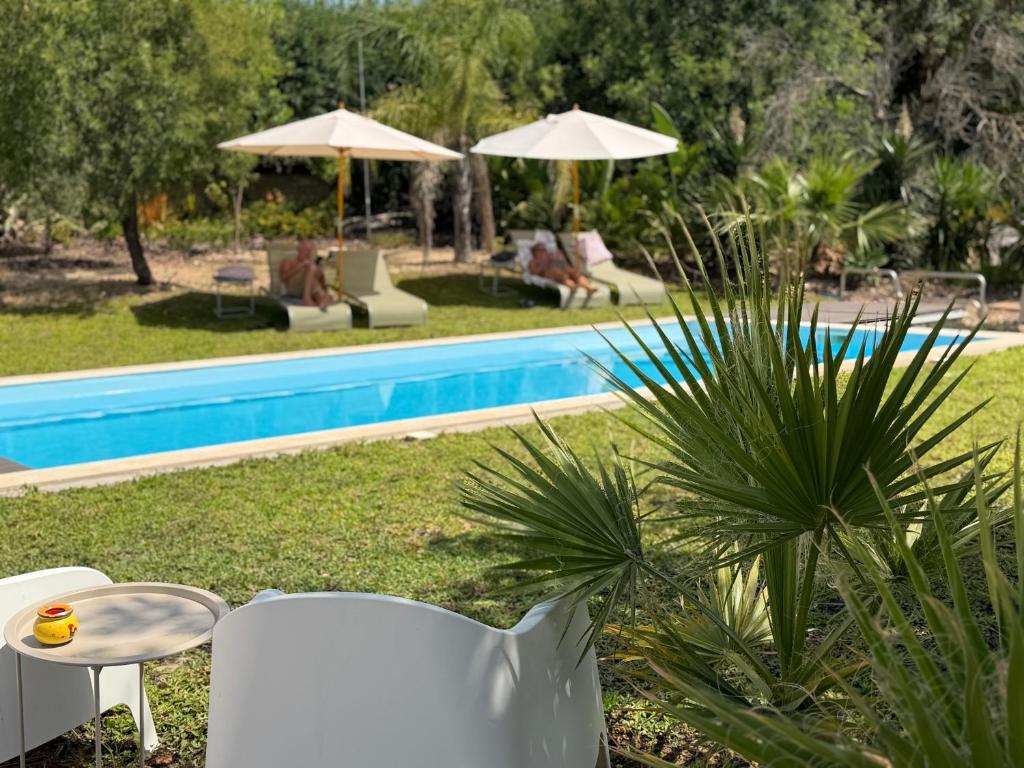 a white table and chairs next to a pool at Boutique Guesthouse-Moncarapacho in Moncarapacho