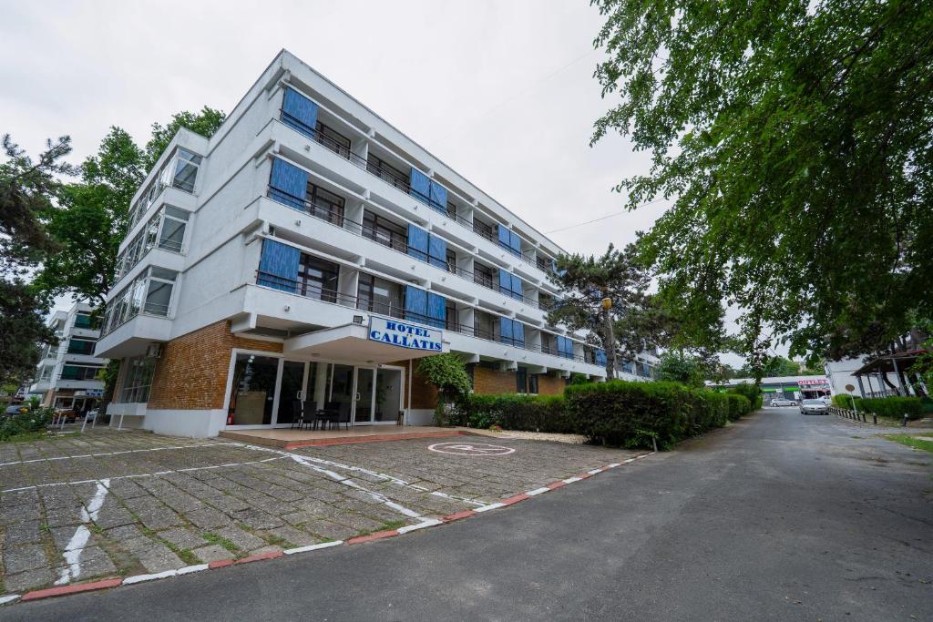 a building with a parking lot in front of it at Hotel Callatis in Neptun