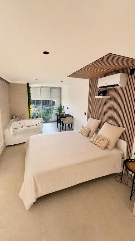 a bedroom with a large white bed and a table at Studio cosy Plage à pied Parking in La Grande Motte