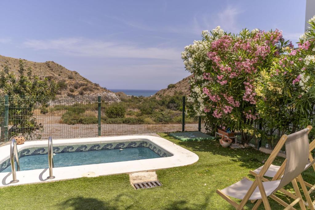 a swimming pool in a yard with a chair and flowers at Sunny Holidays Mojácar Pool House in Mojácar