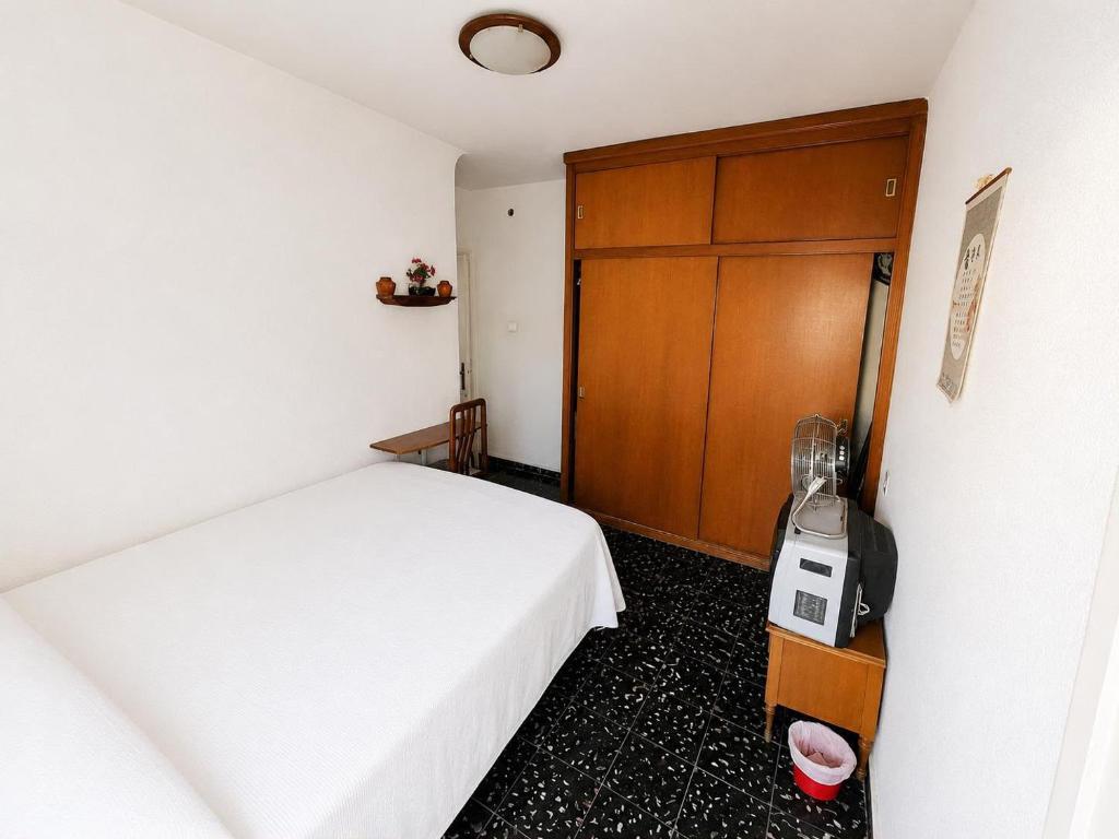 a bedroom with a white bed and a wooden door at Leidy in Alicante