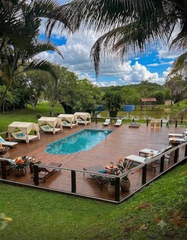 a swimming pool on a wooden deck with chairs and tables at Hotel Fazenda VCP in Silva Jardim