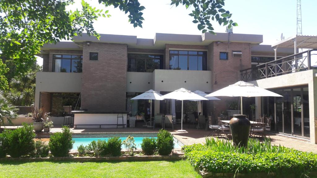 a house with umbrellas and a swimming pool at Willow Banks Lodge in Parys