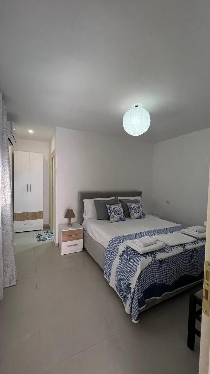 a white bedroom with a large bed and a lamp at Kloa Apartments in Orikum
