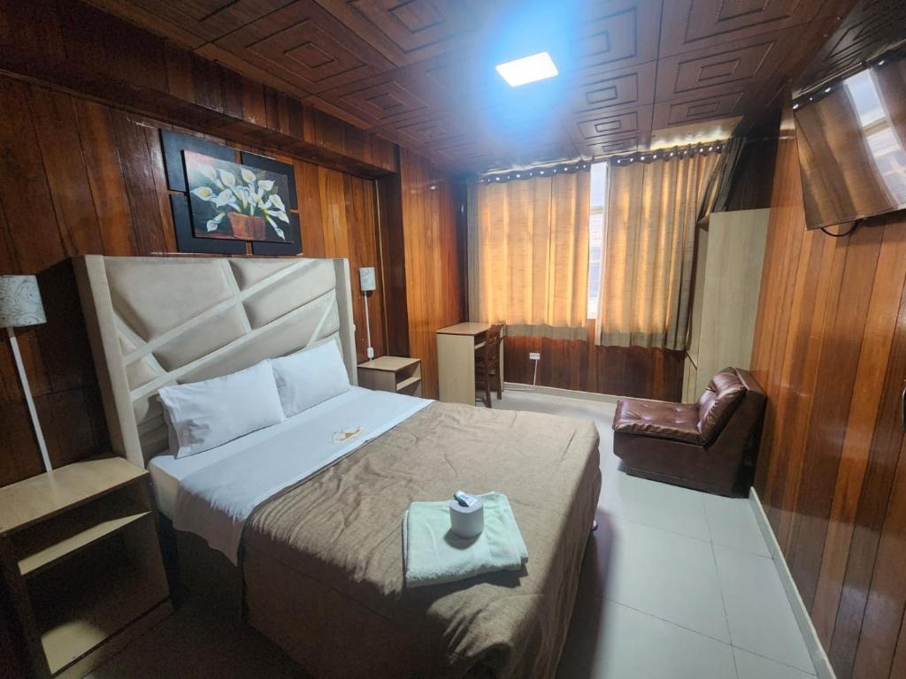 a bedroom with a large bed and a chair at Hotel Palace in Huancayo