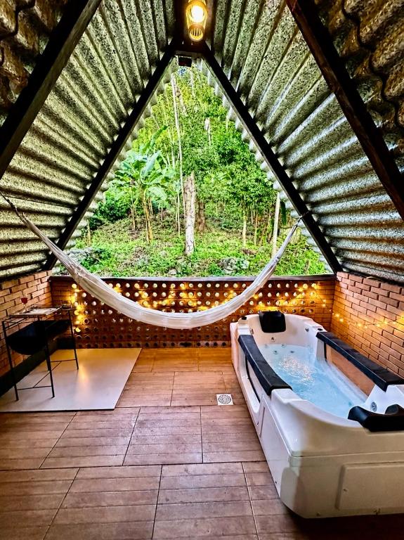 a hammock in a room with a bath tub at Chalé Suíco Nupcial II - Chalés Belo Monte - Pacoti in Pacoti