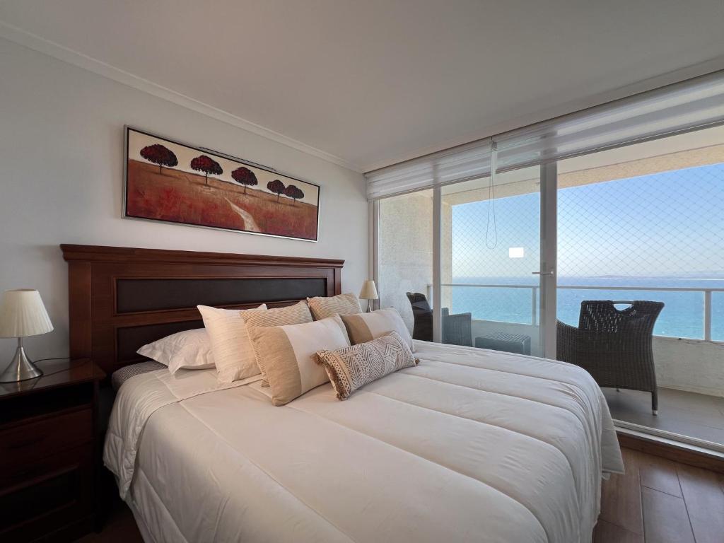 a bedroom with a large bed with a view of the ocean at Oceana Suites Costa Montemar in Concón